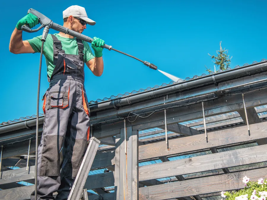 Dakgoot reinigen in Apeldoorn: medewerker van Hezeman reinigt de dakrand en goot Dakgoot reinigen in Apeldoorn: medewerker van Hezeman reinigt de dakrand en goot