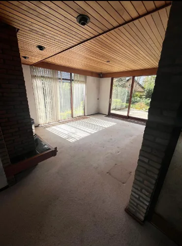 Huisontruiming Epe: lege woonkamer met houten plafond na de ontruiming