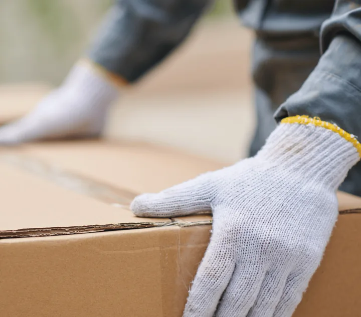 Huisontruiming Zwolle: medewerker met werkhandschoenen pakt een verhuisdoos op