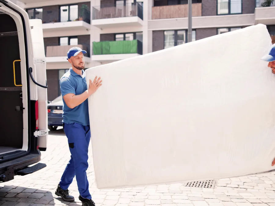 Spoedontruiming: twee verhuizers dragen een matras naar de bestelbus Spoedontruiming: twee verhuizers dragen een matras naar de bestelbus