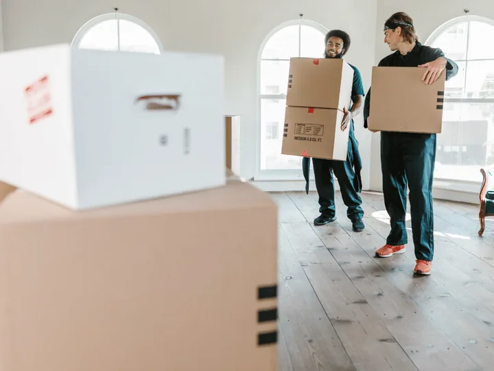 Woningontruiming met spoed: verhuizers dragen dozen door een lichte woonkamer