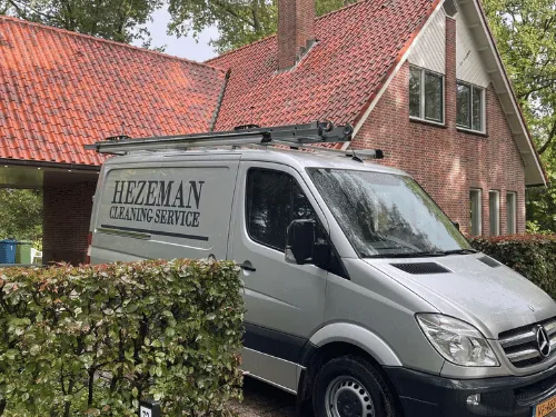 Woningontruiming Twello: de bus van Hezeman Cleaning Service bij een woning met rood pannendak Woningontruiming Twello: de bus van Hezeman Cleaning Service bij een woning met rood pannendak